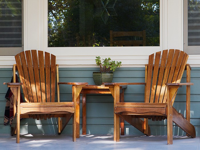 Front home porch with two wooden patio chairs and table.